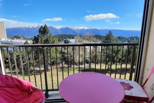 d'un balcon avec une table rose et une vue sur les montagnes. dans l'établissement Joli F4 en lisière de forêt, à Font-Romeu-Odeillo-Via