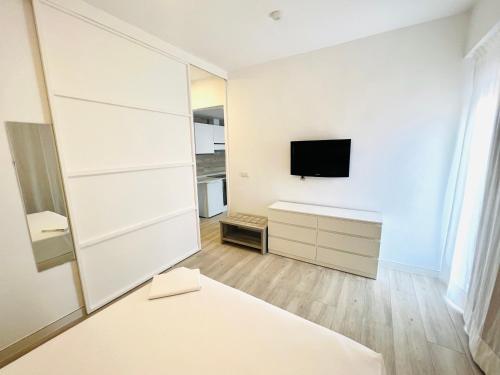 um quarto branco com uma televisão e um espelho em Apartamentos Hotel Puente de Hierro em Benicàssim