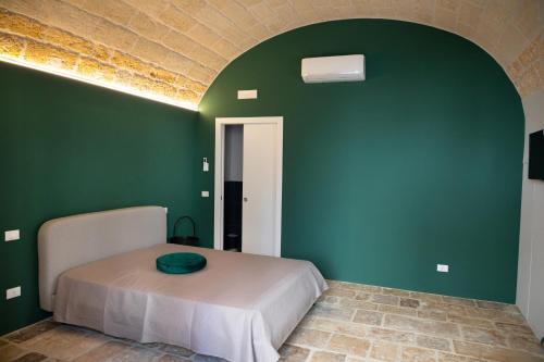 Cette chambre comprend un lit et un mur vert. dans l'établissement Aqua - Letto e Colazione, à Acquaviva delle Fonti