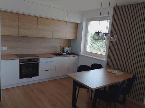 a kitchen with a wooden table and a table and a dining room at Apartament Green Town Rybno Warmia Mazury in Rybno