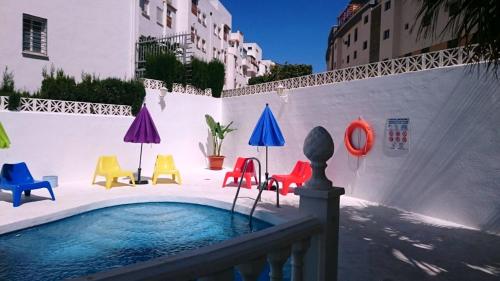 a pool with colorful chairs and umbrellas in a courtyard at Hotel Betania in Benalmádena