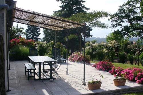 a patio with a table and chairs and flowers at La Maison des Roses in Mareuil-sur-Lay