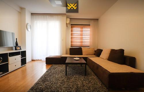 a living room with a couch and a table at Deluxe Apartment 1BR+ with Parking in Prishtinë