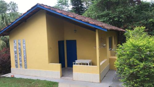 a small yellow house with a blue door at Belas Águas Mairiporã in Mairiporã