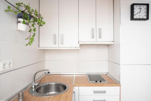 a kitchen with white cabinets and a sink and a clock at EnjoyGranada LUJO Piscina y Parking in Granada