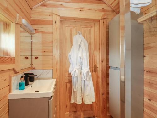 a bathroom with a white robe hanging on a wooden wall at Dragonfly Retreat in Pentney