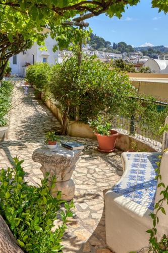 a stone walkway with a bench and some plants at Villa Giardini Luxury Room in Capri