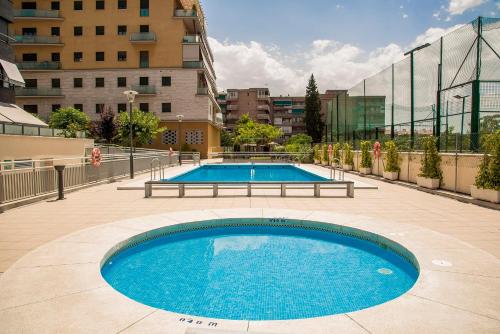 a large swimming pool in a city with buildings at EnjoyGranada LUJO Piscina y Parking in Granada