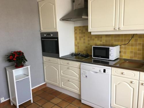 a small kitchen with white cabinets and a microwave at La maison de rolland in Saint-Martin-lʼArs
