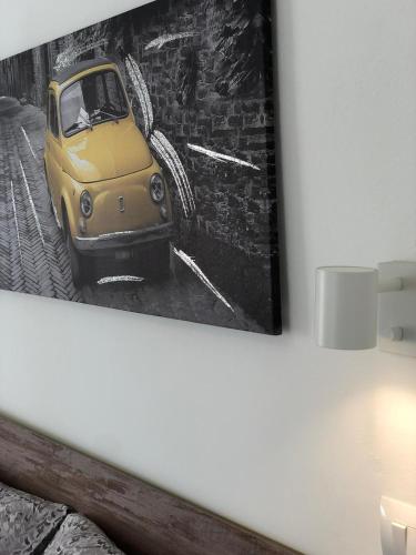 a picture of a yellow car hanging on a wall at Domus Alessia in Monserrato