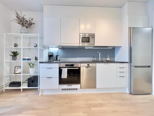 a kitchen with white cabinets and a stainless steel refrigerator at Stunning Central Apartment Helsinki in Helsinki