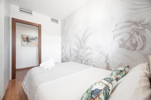 a bedroom with a white bed with a tropical wallpaper at EnjoyGranada LUJO Piscina y Parking in Granada