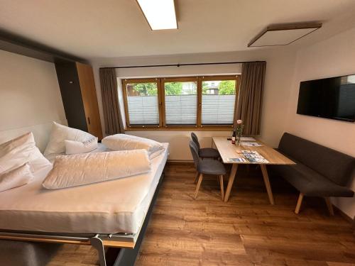 エールヴァルトにあるApart Baderのベッド、テーブル、テレビが備わる客室です。