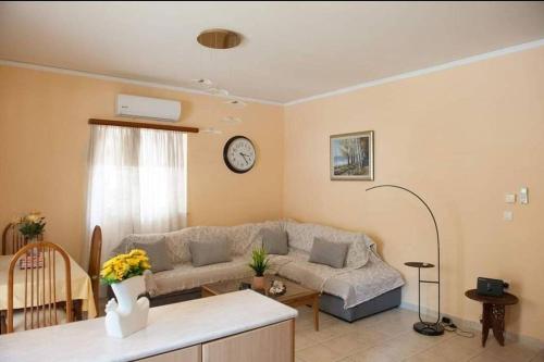 a living room with a couch and a clock on the wall at Meropi Apartment in Preveza