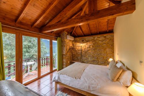 una camera da letto con un letto in una stanza con finestre di Gerês Country Stays - Sequeiro a Rio Caldo