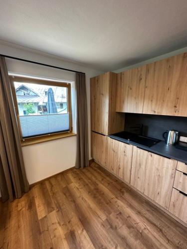 eine Küche mit Holzschränken und einem Fenster in der Unterkunft Apart Bader in Ehrwald