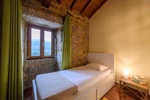 ein kleines Schlafzimmer mit einem Bett und einem Fenster in der Unterkunft Gerês Country Stays - Sequeiro in Rio Caldo