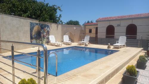 a large swimming pool with chairs and a wall at Villa Naima in Larache