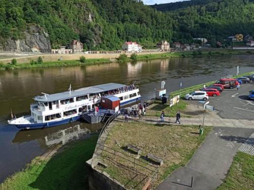 a boat is docked in a river next to cars at U Bocmana s výhledem na zámek a Labe in Děčín