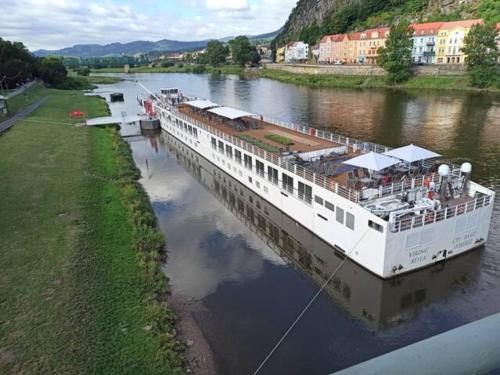 a large boat is docked on a river at U Bocmana s výhledem na zámek a Labe in Děčín
