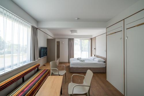 a bedroom with a bed and chairs and a window at Vellamo Dębki in Dębki