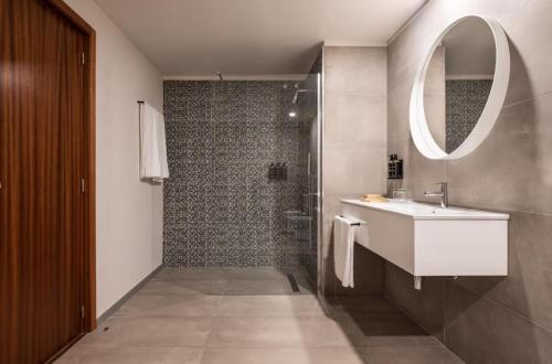 a bathroom with a sink and a shower with a mirror at Exe Praia Golfe in Espinho