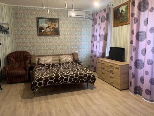 um quarto com uma cama, uma televisão e uma cadeira em Moskovs'kyi Avenue 80/82 em Kharkov