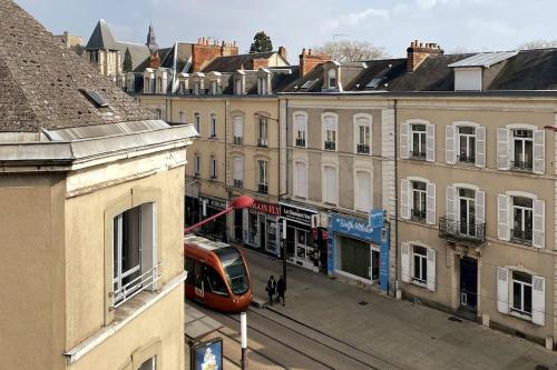 a train on a street in a city with buildings at Le Bali Appart' T1 au centre du Mans in Le Mans