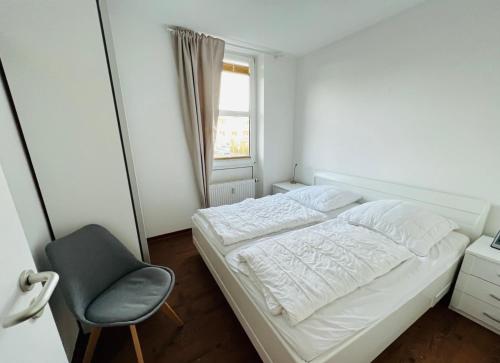 een kleine slaapkamer met een bed en een stoel bij HR Nordwind in Laboe