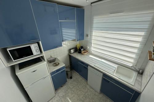 Elle comprend une petite cuisine avec des placards bleus et un four micro-ondes. dans l'établissement Spacious 68m apartment bright and charming, au Pouliguen