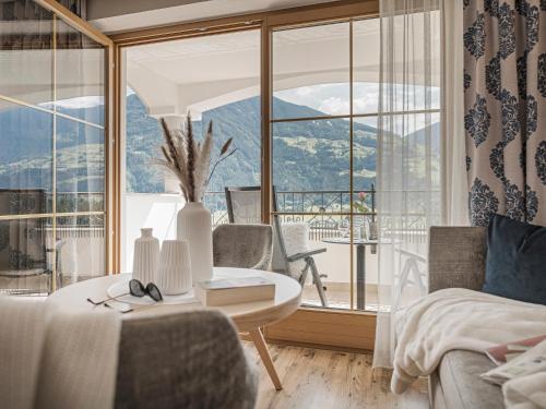 a room with a bed and a table and a large window at Platzlhof - Mein Hotel im Zillertal in Ried im Zillertal