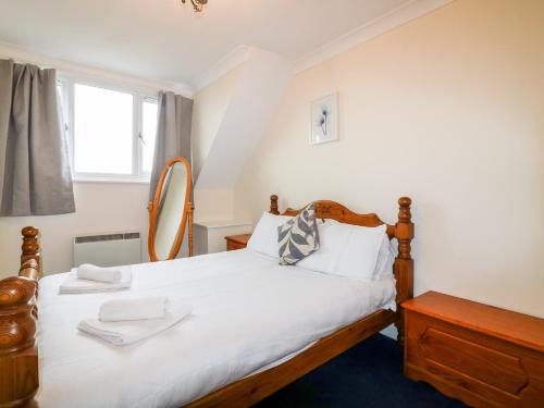 a bedroom with a bed with white sheets and a window at Shoreline House in Fraserburgh