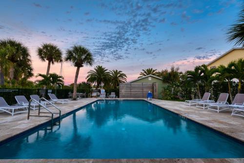 a swimming pool with chairs and palm trees at Escape Coastal Resort on Casey Key in Nokomis