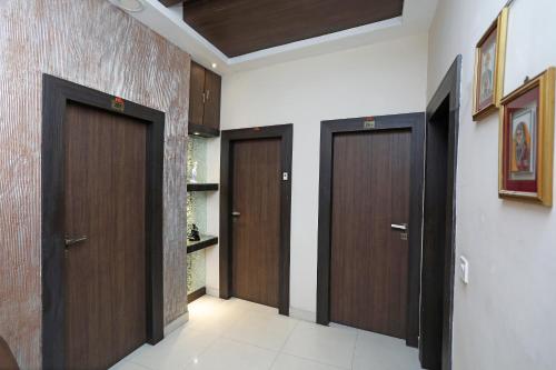 a hallway with three wooden doors in a room at Hotel South Fern in Ballygunge