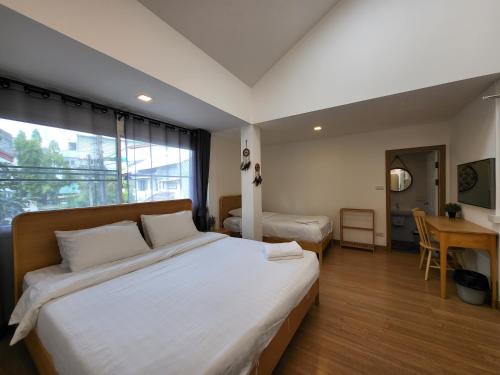 Schlafzimmer mit einem großen weißen Bett und einem Schreibtisch in der Unterkunft Nimman home 4 bedroom near One Nimman in Chiang Mai