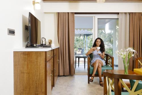 a woman sitting in a chair in a kitchen at Whistling Woodzs Resort in Dandeli