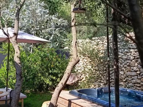 a swimming pool in a garden with a tree at Hôtel Les Suites Du Maquis in Bonifacio