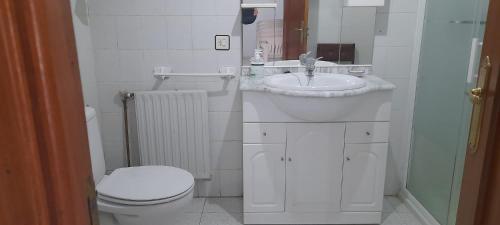 Baño blanco con lavabo y aseo en Sol Poniente, en La Fregeneda