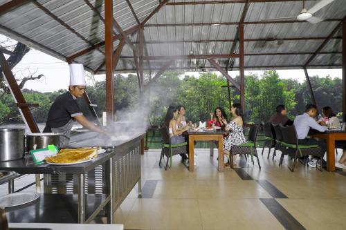 a man cooking food on a grill in a restaurant at Whistling Woodzs Resort in Dandeli