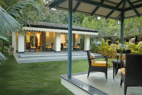 a house with a patio with chairs and tables at Whistling Woodzs Resort in Dandeli