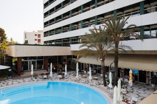 a swimming pool in front of a building with a palm tree at Grand Hotel Del Mare Resort & Spa in Bordighera