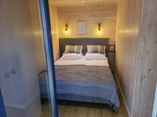 małą sypialnię z łóżkiem w drewnianej ścianie w obiekcie Morska Przystań Pilëce w Jastrzębiej Górze