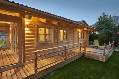 a wooden cabin with a deck with green chairs at Chalet Bergheimat in Wegscheid