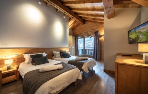 two beds in a hotel room with a tv at Chalet du Samoyède in Morzine