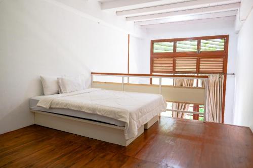 a white bedroom with a bed and a window at Jawa Dwipa Heritage Resort in Tawangmangu