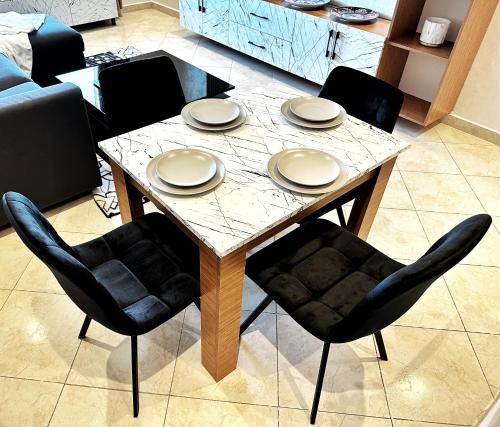 a table with chairs and plates on top of it at Magnifique appartement en plein centre ville in Kenitra