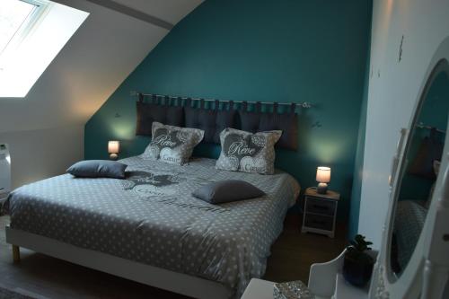 een slaapkamer met een bed met kussens en een blauwe muur bij ô temps de l'escapade in Saint-Père-sur-Loire