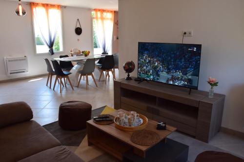 een woonkamer met een flatscreen-tv en een tafel bij ô temps de l'escapade in Saint-Père-sur-Loire