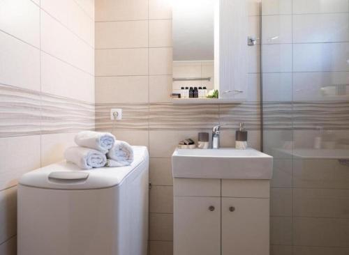 uma casa de banho branca com um lavatório e um espelho em Atalanti Seaside Junior Suites em Keratokambos