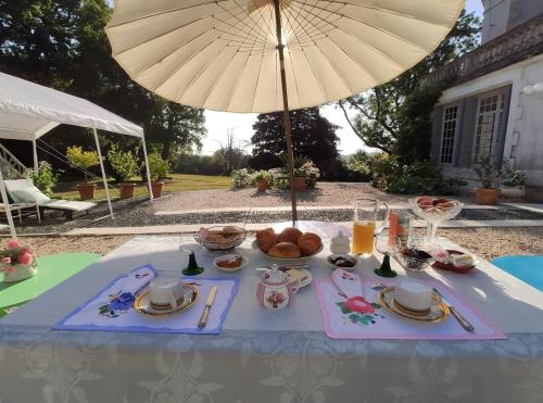 una mesa con una bandeja de comida y una sombrilla en La Suite Venise au Château de Saint-André, en Mareuil-sur-Lay